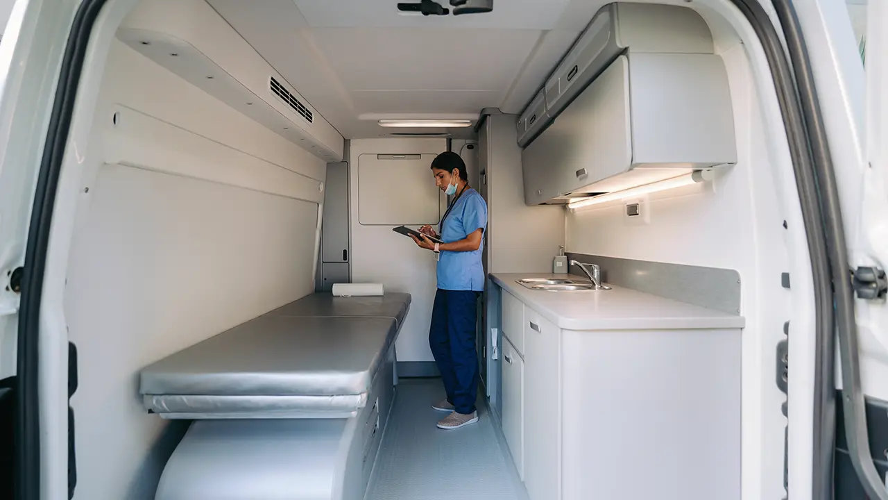 Interior ilustrativo de una unidad médica móvil con espacio de consulta y almacenamiento