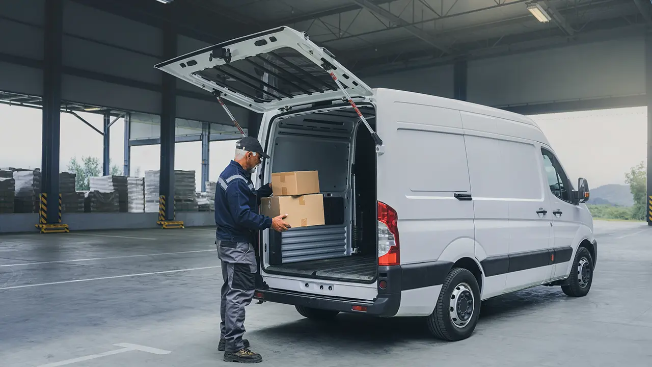 Van de trabajo con portón trasero abierto bajo una cubierta de carga