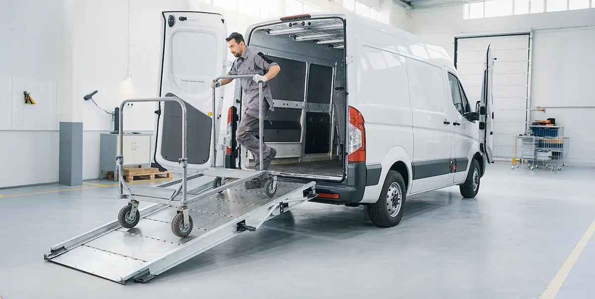 Van de trabajo con una rampa desplegada para movilizar un carro con ruedas